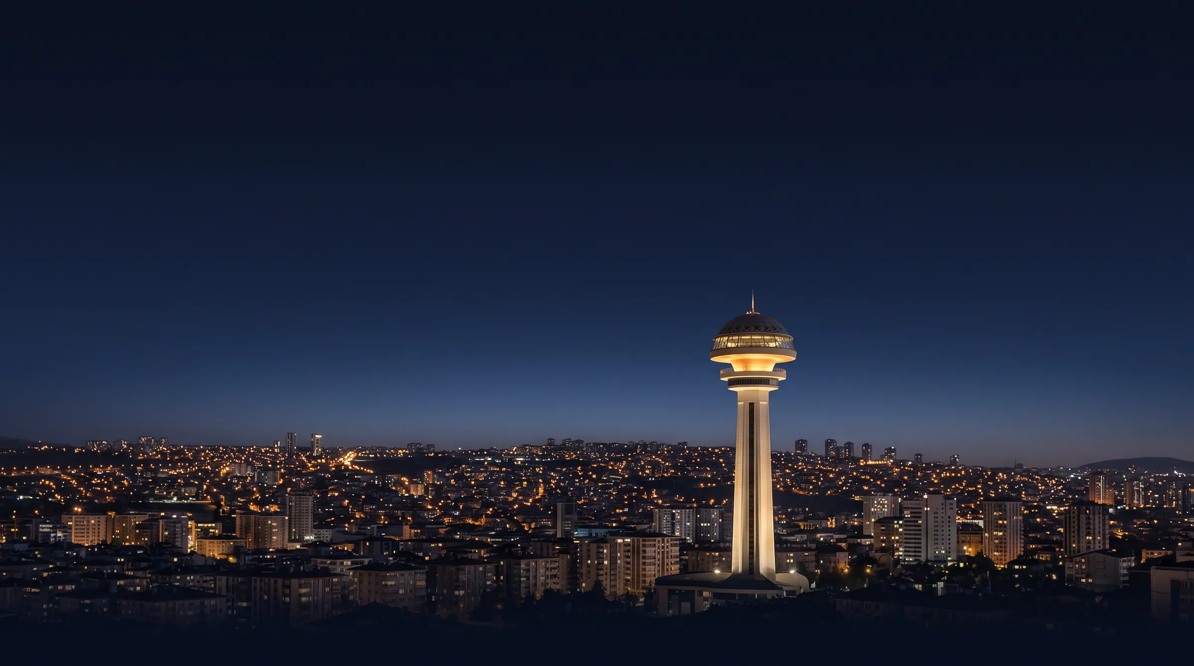 Ankara cityscape and Atakule illuminated by golden city lights during the blue hour after sunset.